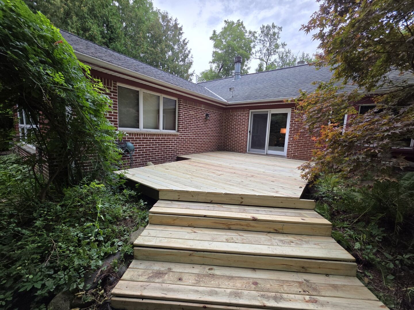 Fresh deck boards and steps installed beside a brick home