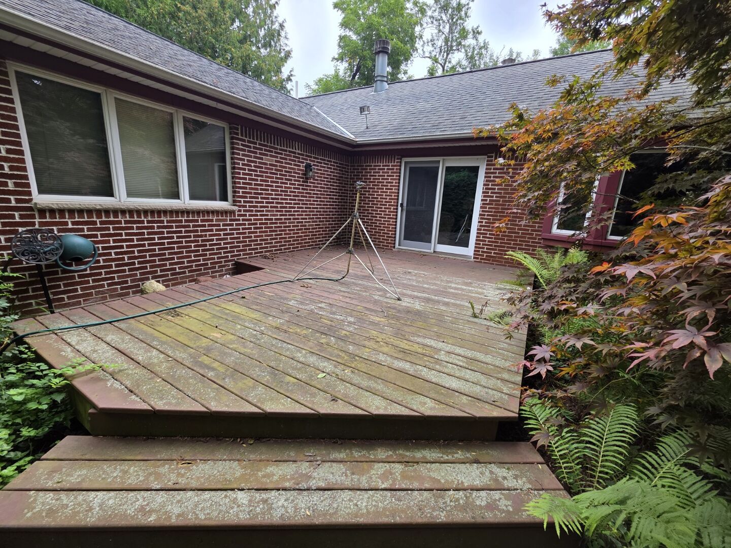 Worn outdoor deck surface before removal, with weathering and moss visible