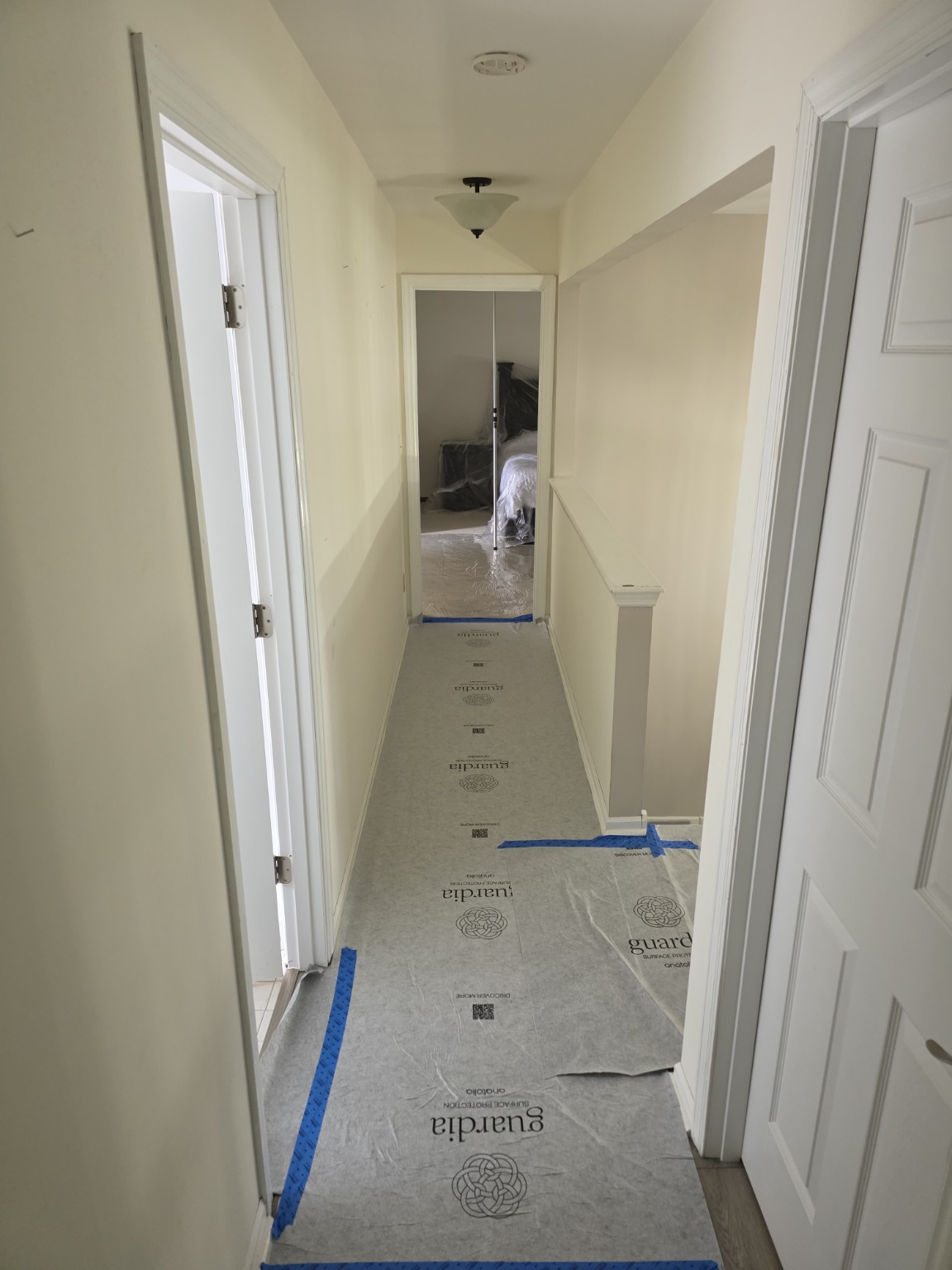 Taped surface protection covering a hallway floor leading to a work area