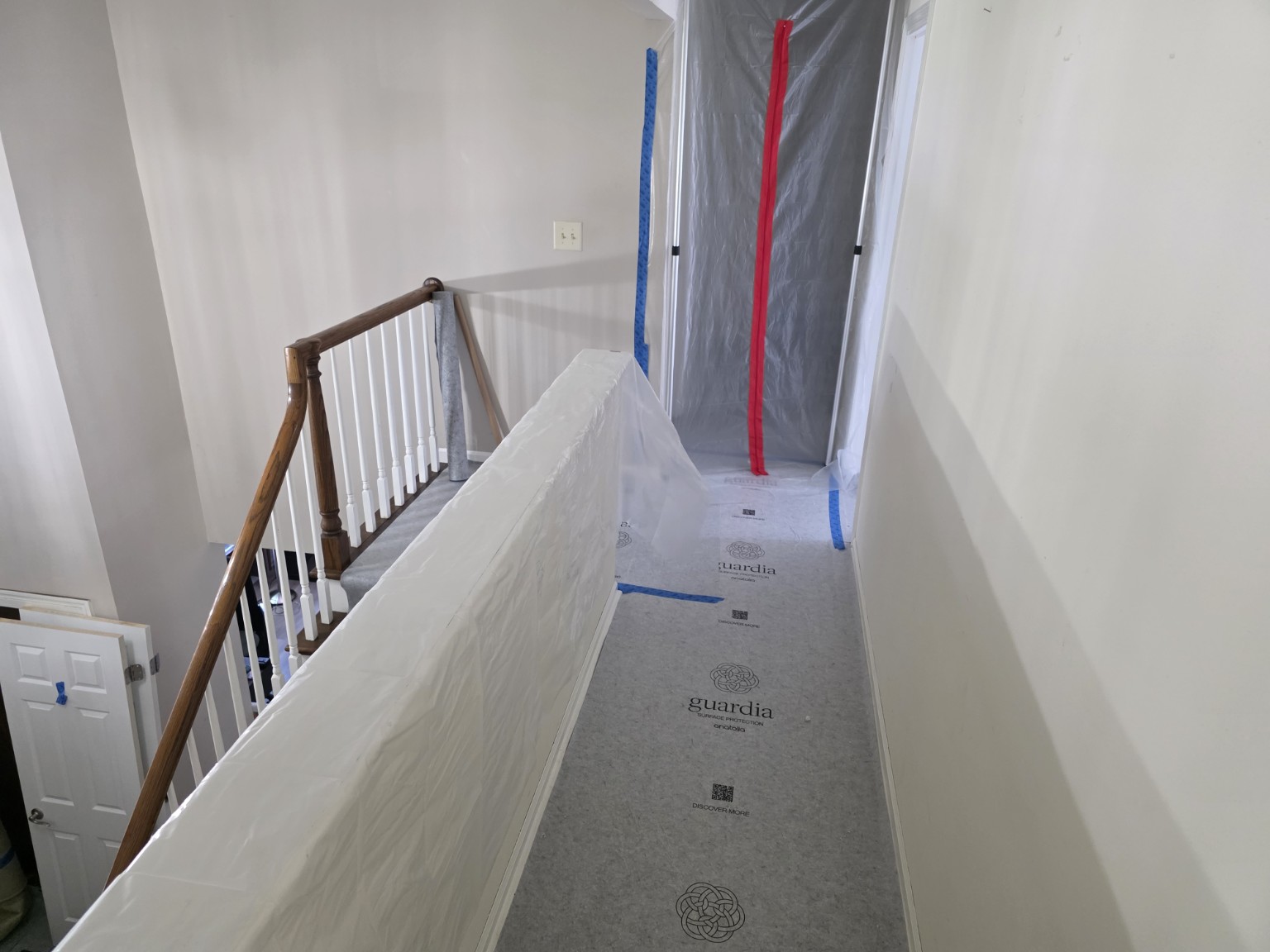 Plastic sheeting protects a railing beside a covered interior walkway